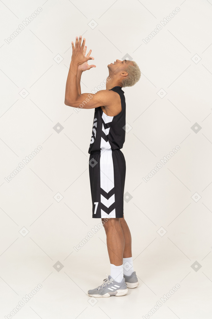 Side view of a praying young male basketball player raising hands