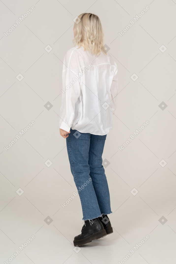 ジャンプするカジュアルな服を着た若い女性の背面図