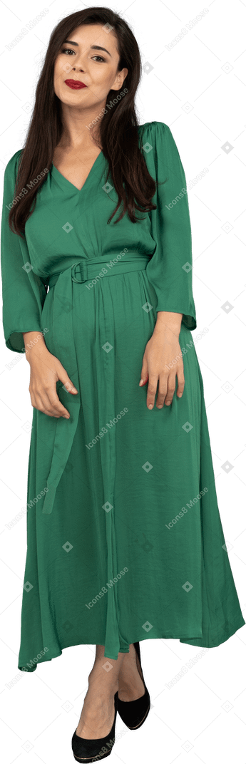 Vista frontale di una timida giovane donna sorridente in abito verde