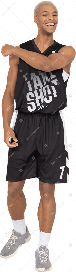 Vista frontale di un giovane giocatore di basket maschio sorridente che tocca la spalla