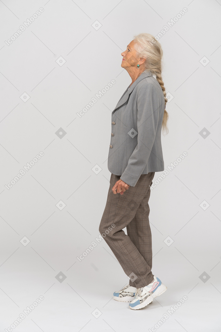 Vista laterale di una vecchia signora in abito in piedi su una gamba sola