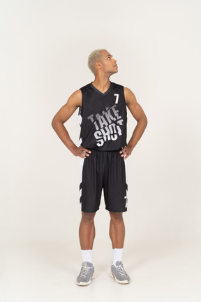 腰に手を置いて見上げる若い男性バスケットボール選手の正面図