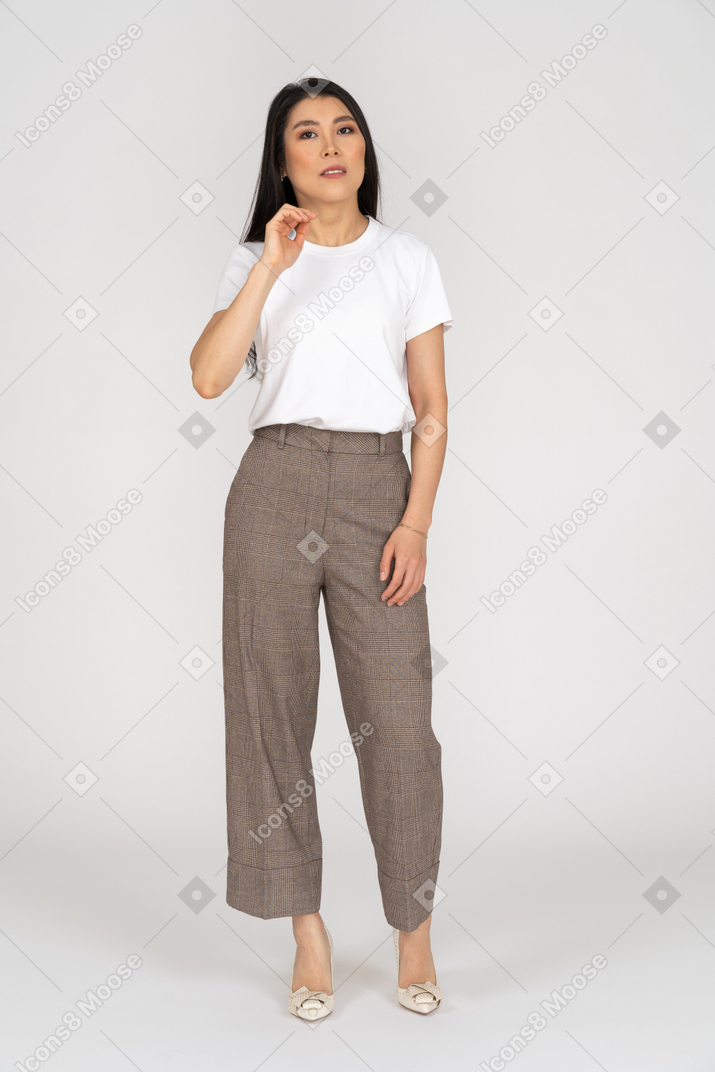 Front view of a perplexed young lady in breeches and t-shirt raising her hand