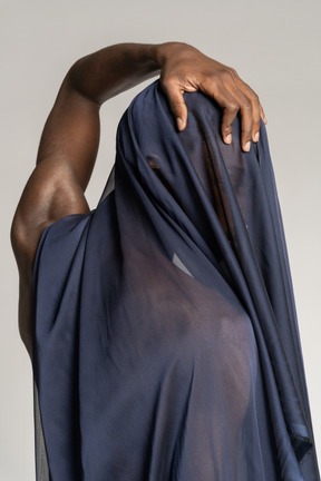 Back view of a young afro man covered with a dark blue shawl touching his head