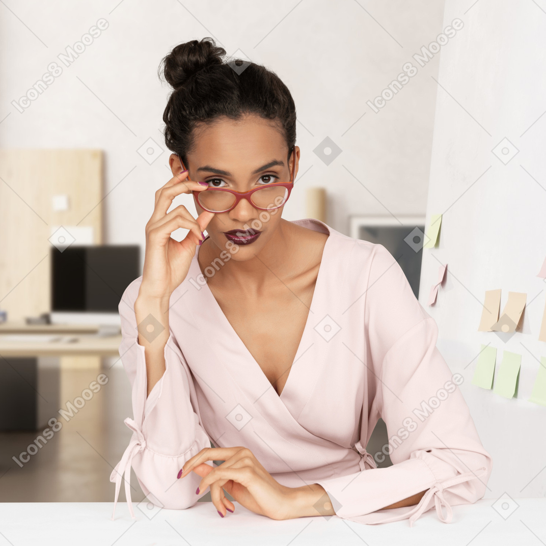 A woman in glasses sitting at a desk in an office
