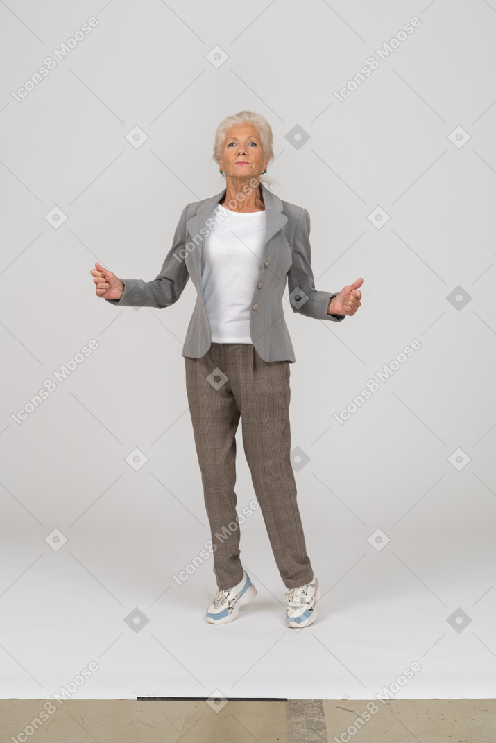 Front view of an impressed old lady in suit standing on toes
