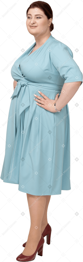 Side view of a woman in blue dress posing with hands on hips