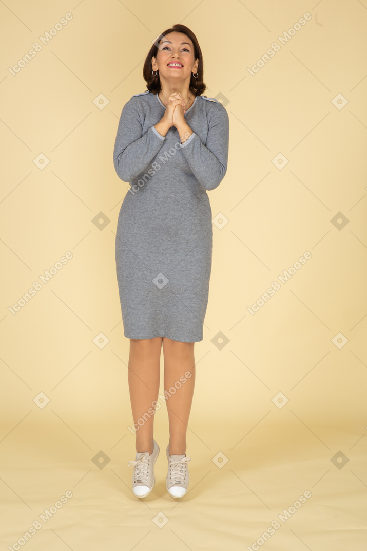 Vista frontal de una mujer vestida de gris haciendo gesto de oración