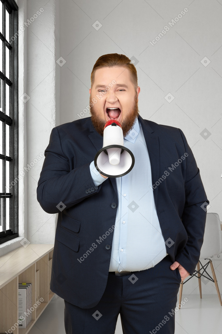A man in a suit is shouting into a megaphone in an office
