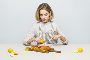 Ragazza seduta al tavolo e cucinare una torta al limone