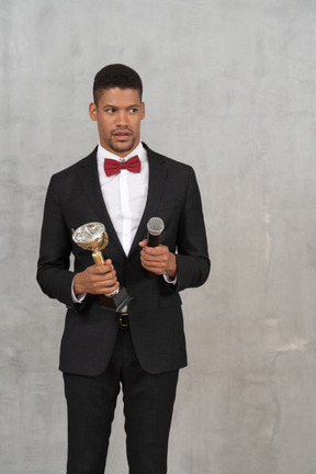 Shocked man holding an award and a microphone