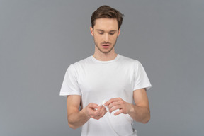 Front view of a young man unfolding facial mask