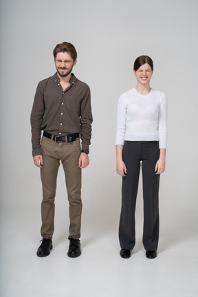 Vista frontal de um jovem casal descontente com uma careta em roupas de escritório