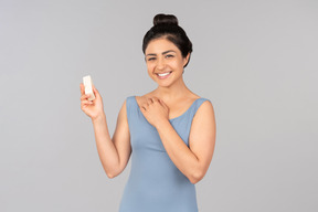 Smiling young indian woman holding face cream