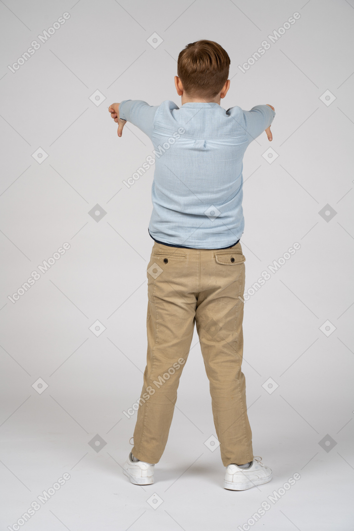 Vista traseira de um menino mostrando os polegares para baixo