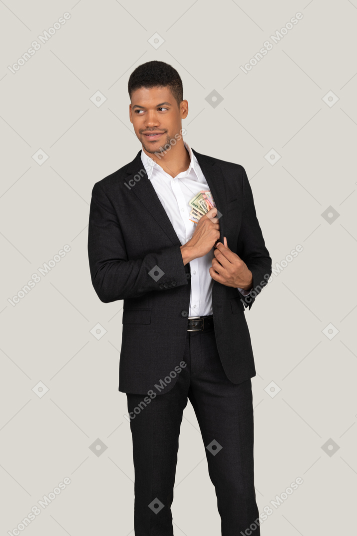Vorderansicht eines jungen mannes im schwarzen anzug, der banknoten in die tasche steckt