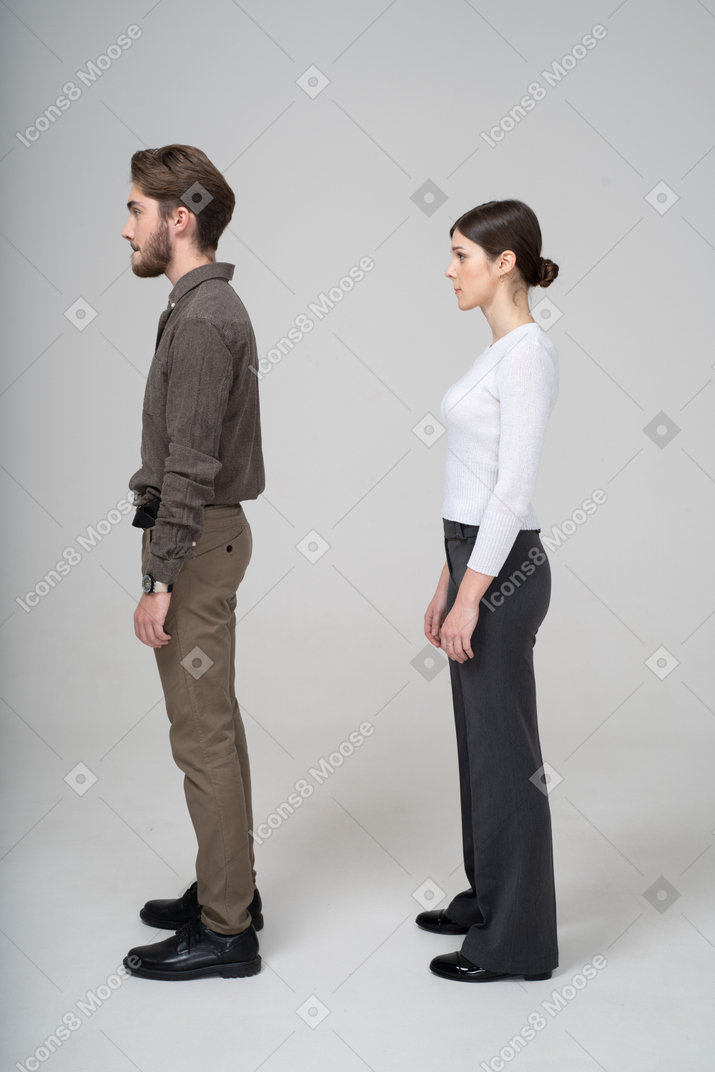 Side view of a young couple in office clothing pressing lips