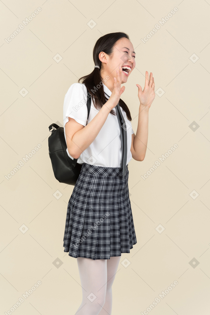 Menina da escola asiática rindo com as mãos abertas
