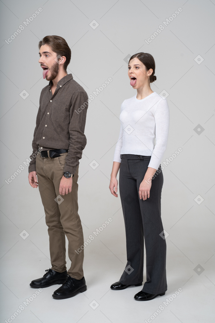 Three-quarter view of a crazy young couple in office clothing showing tongue