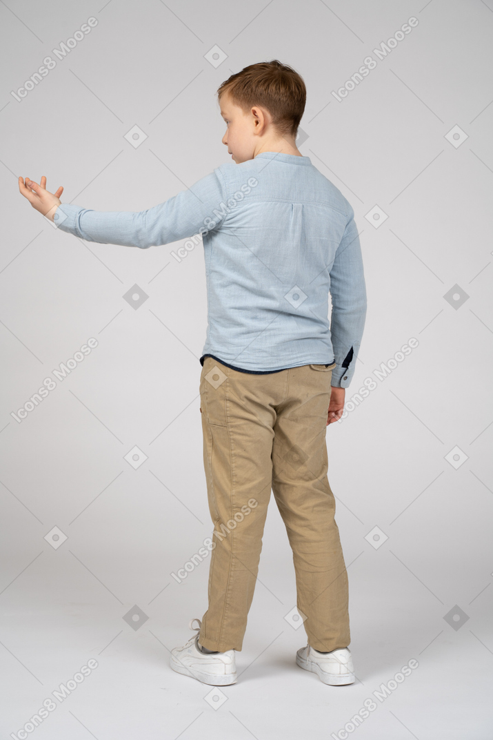 Vista posteriore di un ragazzo in piedi con il braccio esteso