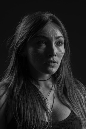 Three-quarter dark portrait of a young  hopeful woman with face art