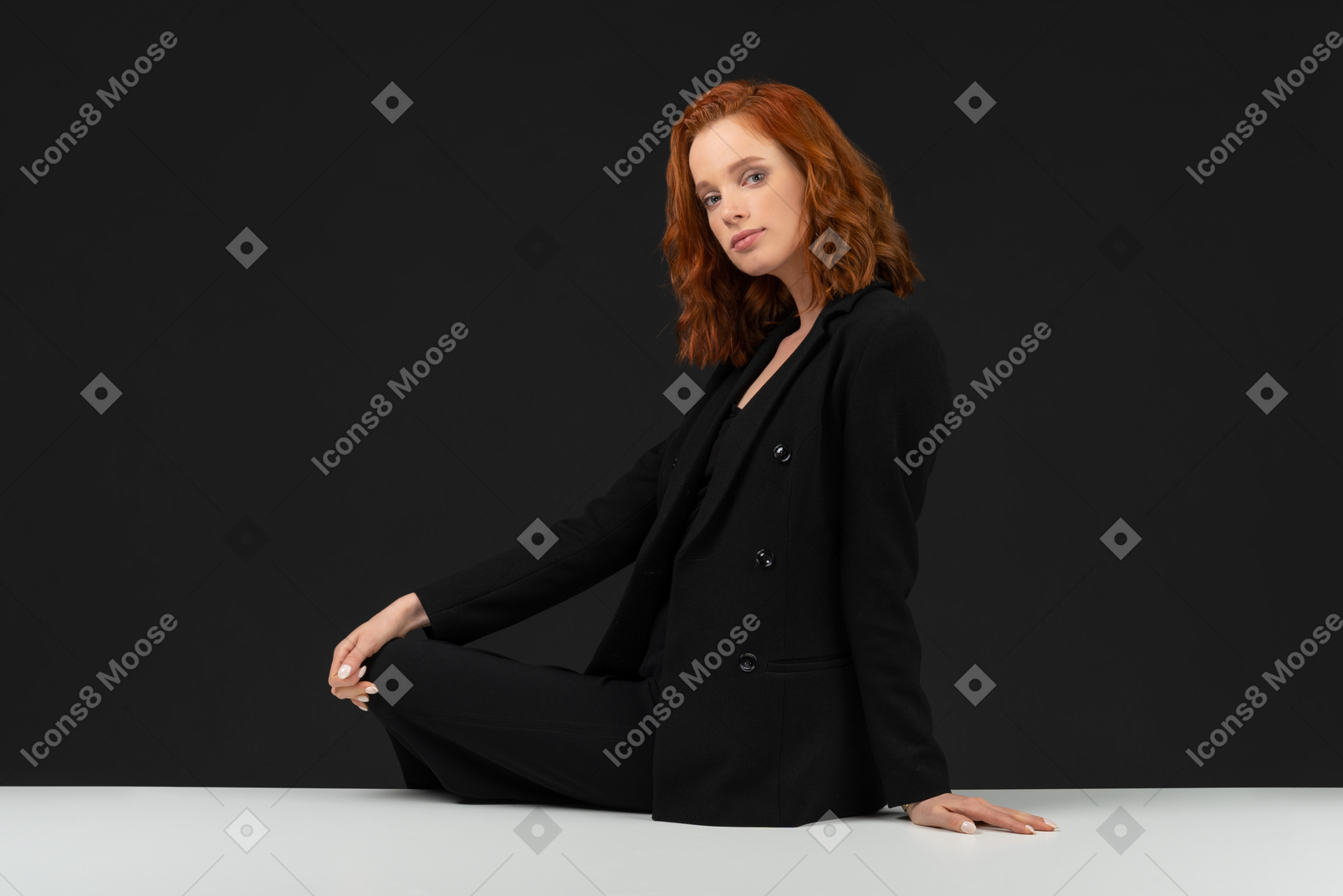 A side view of the beautiful woman sitting on the table and holding her hand on knee
