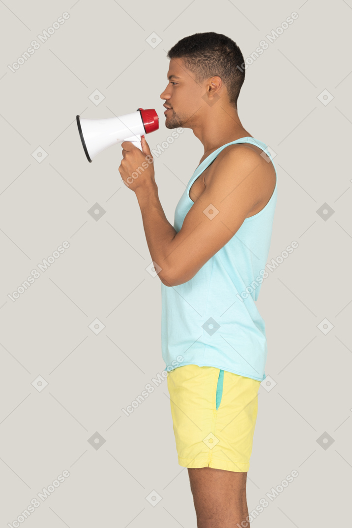 A man in a blue shirt and yellow shorts holding a red and white megaphone