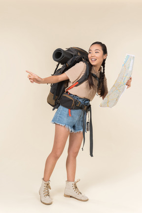 Female asian hiker holding map and looking aside