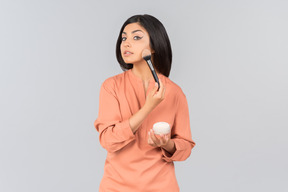 Indian woman applying face powder on her cheeks