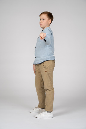 Vista lateral de um menino apontando com o dedo