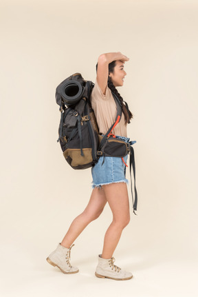 Amazed young asian hiker standing in profile with huge backpack