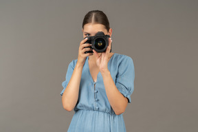 Front view of a young woman in blue dress taking shot