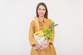 Young woman holding reusable shopping bag with vegetables