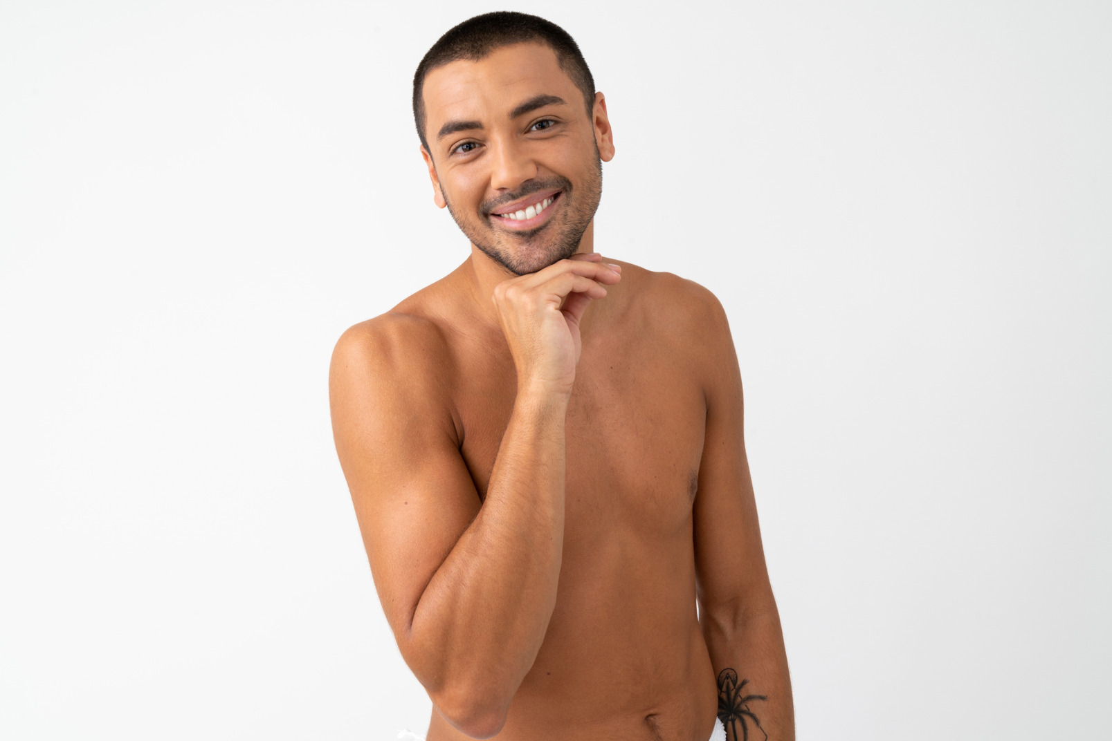 Barechested young man with a nice smile touching his chin