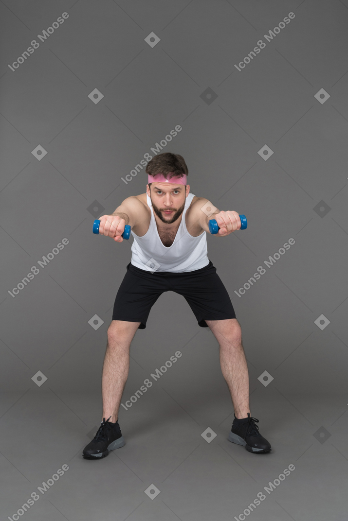 Sporty man doing arm exercises using blue dumbbells