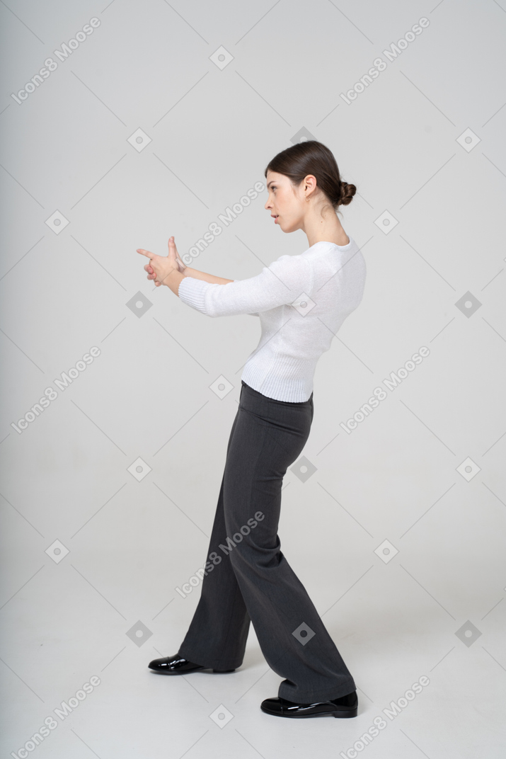 Side view of woman aiming with finger gun