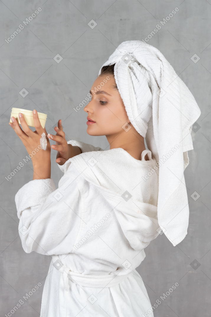 Женщина в халате наносит крем для рук