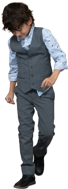 Vista frontal de un niño con traje gris caminando hacia adelante