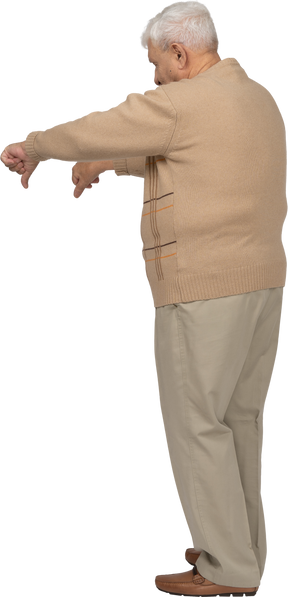 Side view of an old man in casual clothes showing thumbs down