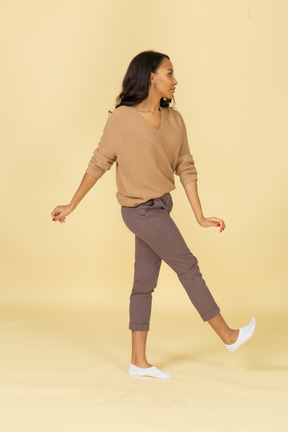 Vista lateral de una mujer joven de piel oscura levantando la pierna