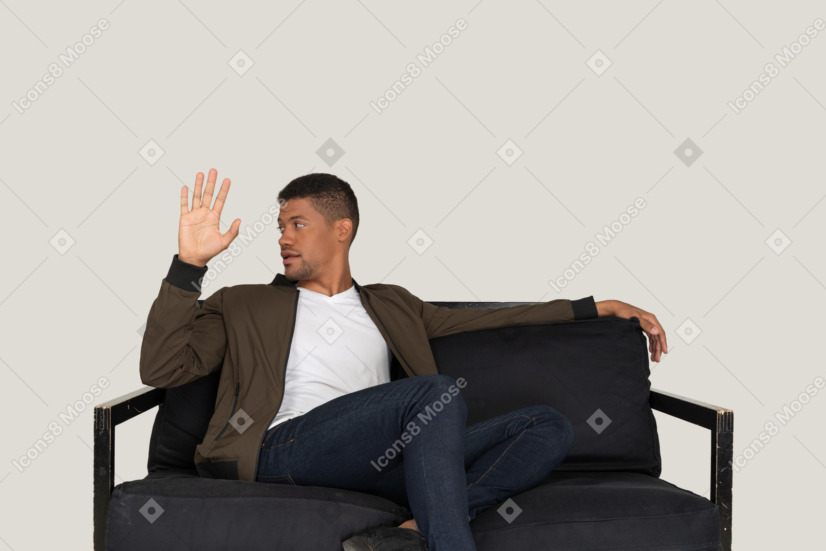 Young man sitting on the sofa and raising a hand
