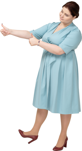 Vista frontal de uma mulher de vestido azul mostrando os polegares para cima