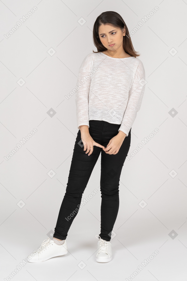 Front view of an offended young indian female in casual clothes holding hands together