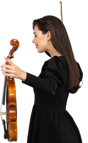 Vista lateral de una violinista en vestido negro extendiendo las manos