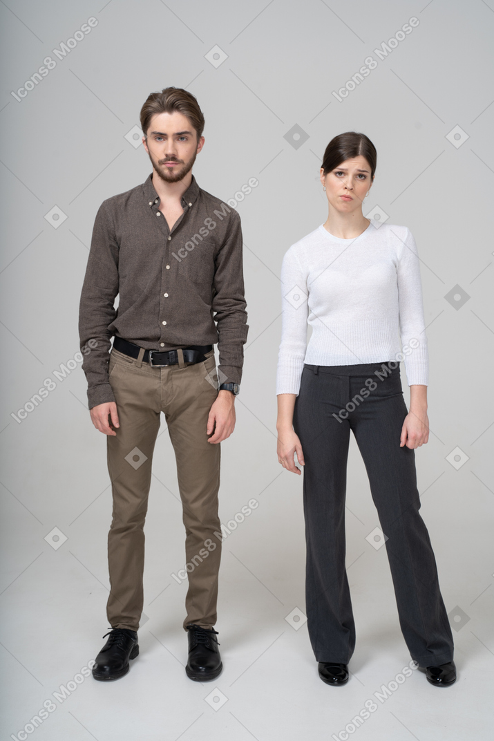Front view of a displeased young couple in office clothing