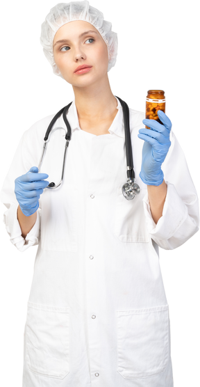 Vista frontal de una joven doctora sosteniendo un frasco de pastillas