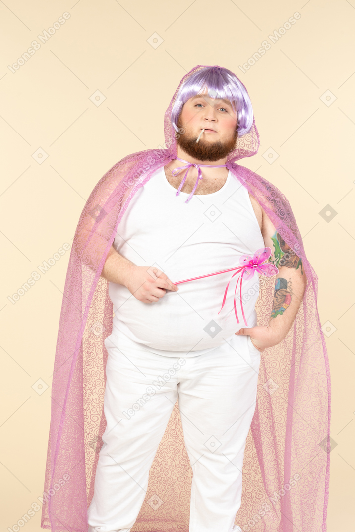 Young plump man dressed as a fairy smoking a cigarette