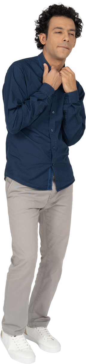 Vista frontal de um homem em roupas casuais tocando o colarinho de sua camisa