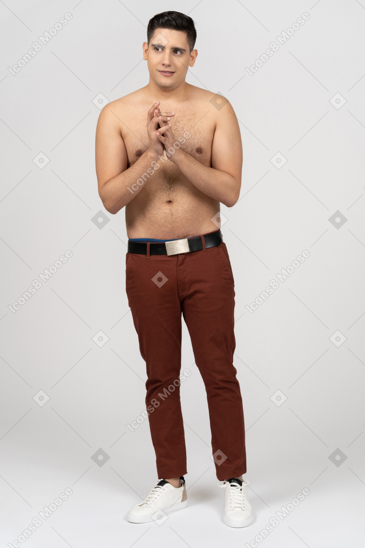 Vista frontal de un hombre latino sin camisa uniendo las manos inseguro