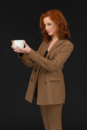 Улыбающаяся женщина в костюме с кружкой кофе